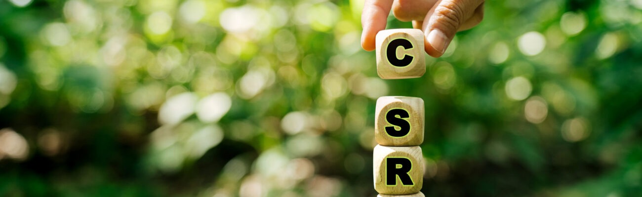 Hand stacking wooden letter blocks spelling CSRD on a mound of moss